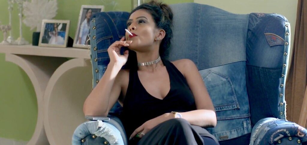 Nia Sharma in cut sleeves deep neck dress sitting on a sofa and smoking - tv serial actress who smoke in real life