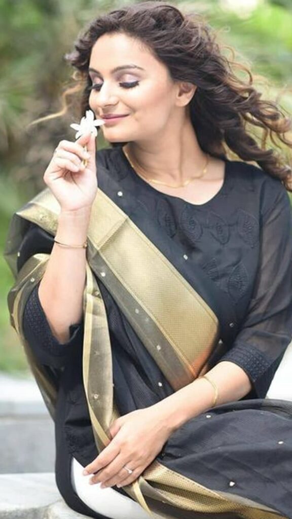 Dimpy Ganguly in black and golden suit smelling a flower - tv celebrities who smoke