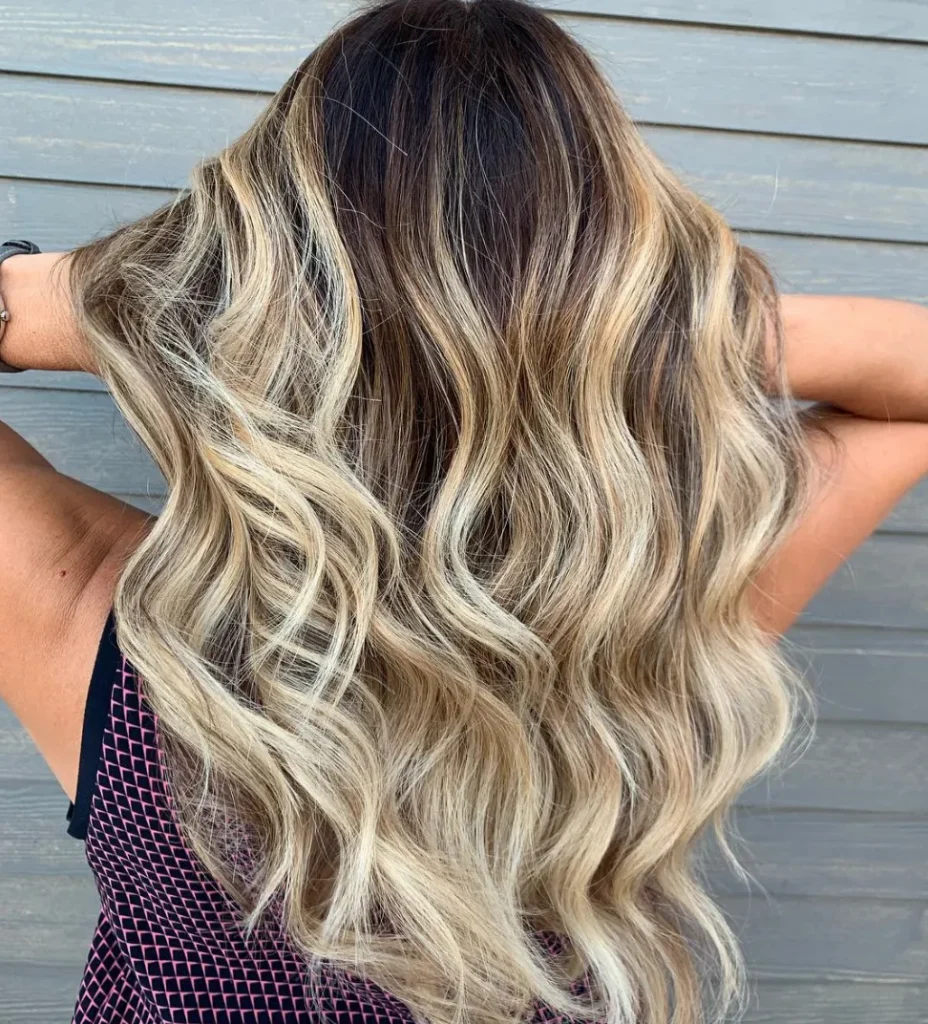 Woman in black and pink dress showing the back view of her Balayage shoulder length haircut - 2022 trendy haircuts