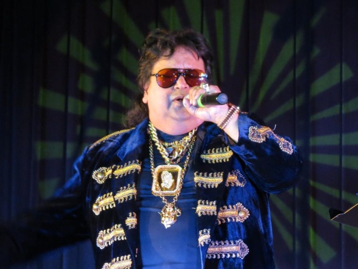 Bappi Lahiri in blue shining jacket with lots of golden necklace and goggles performing on stage - indian actors who died in 2022