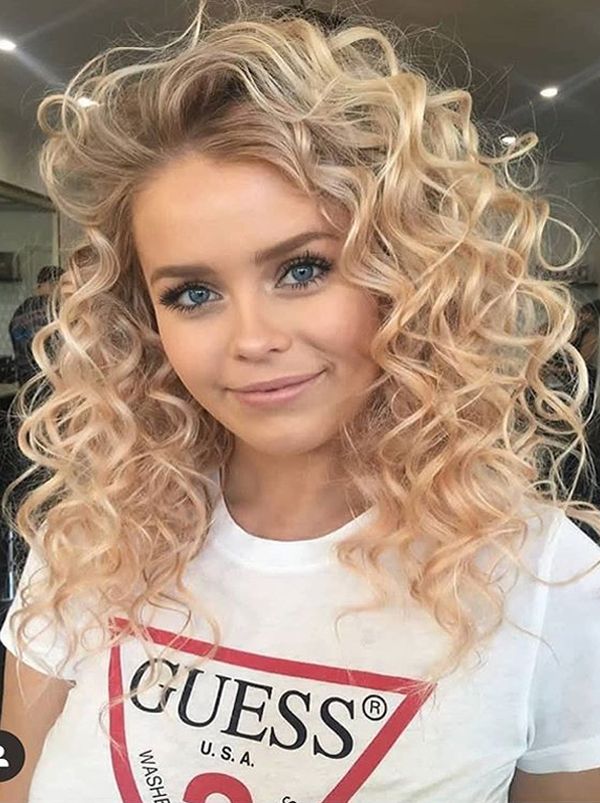 woman in white printed t-shirt and Bouncy Curls hairstyle - 2022 haircuts female