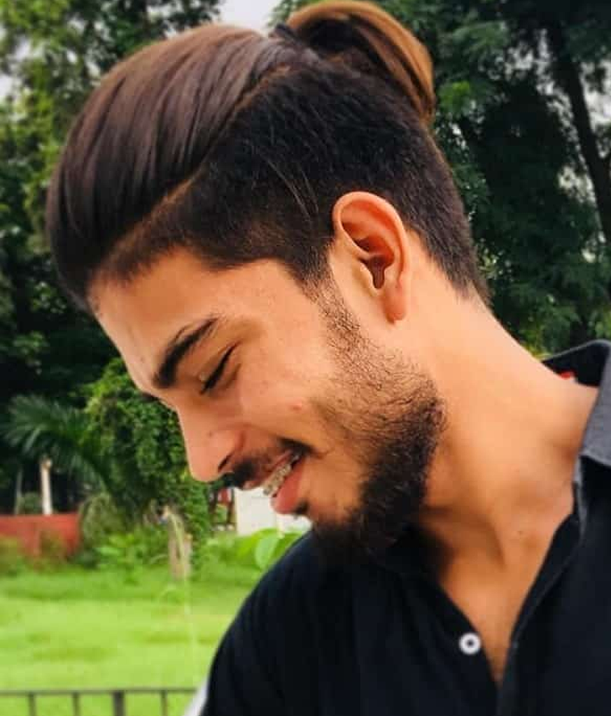 Smiling boy in black shirt and Ponytail hairstyle - best haircut for Indian boy