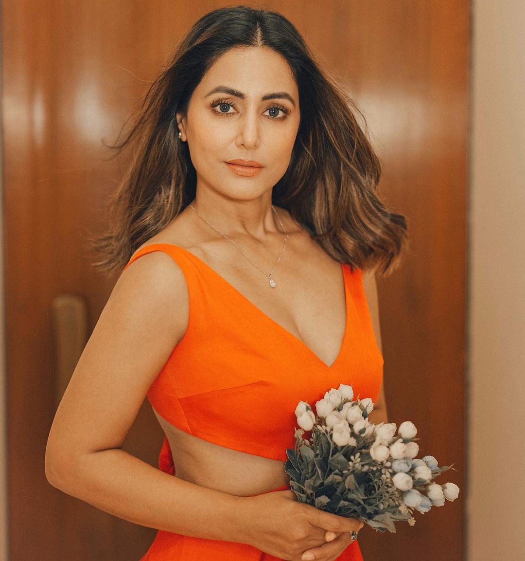Hina Khan in orange dress holding flowers and posing for camera - Most beautiful Indian Girls