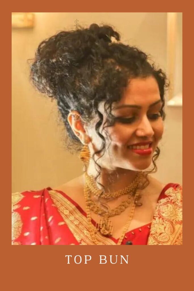 Smiling woman in red lehenga with golden jewellery and Top Bun hairstyle -  curly hair with lehenga