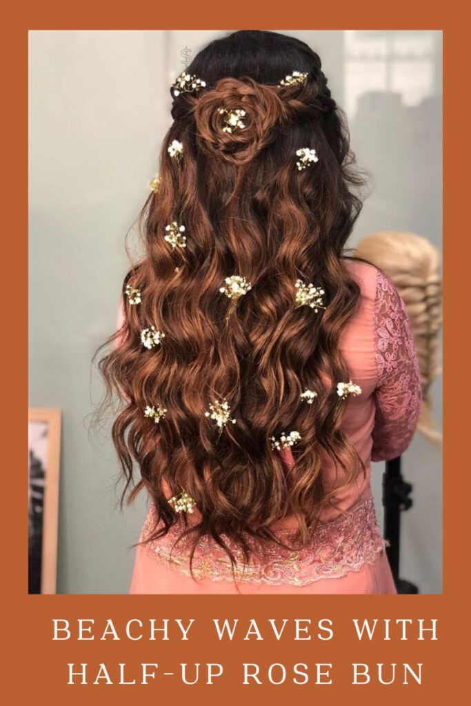Woman in pink lehenga showing the back view of her Beachy Waves with half-up Rose Bun hairstyle - lehenga hairstyles for curly hair