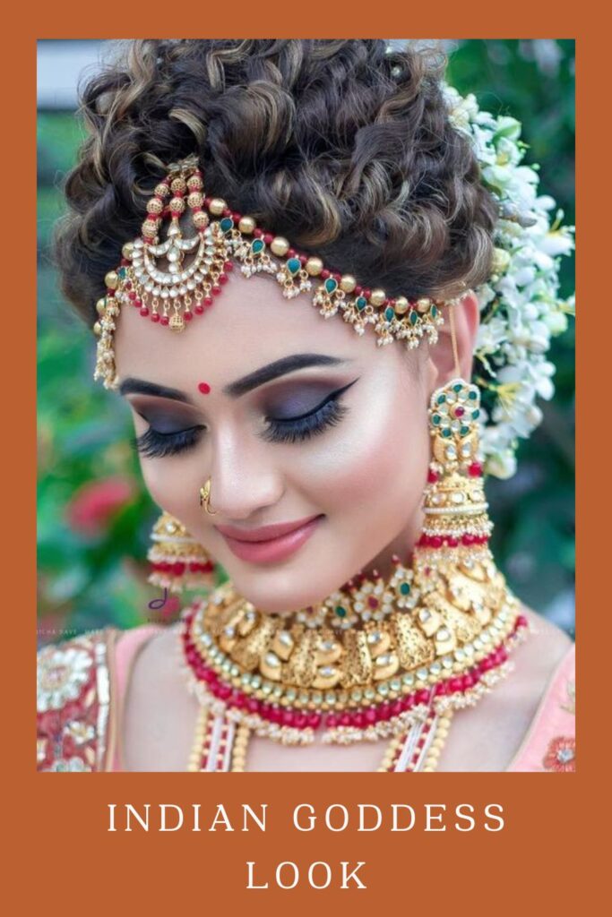 Gajra topuzlu ve Hint Tanrıçası Görünümünü sergileyen çok renkli altın mücevherli kadın - Orta boy saçlar için lehengalı saç modeli